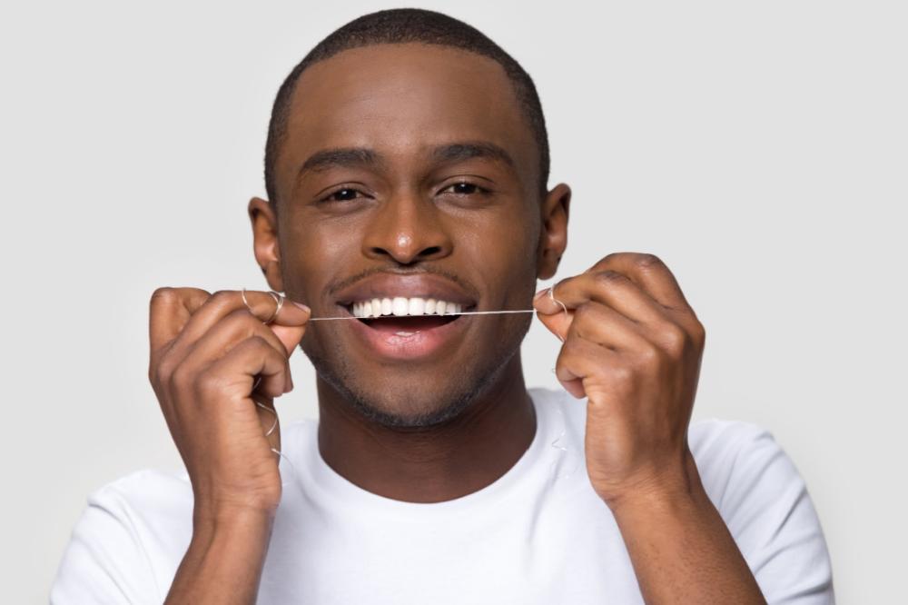 Man flossing his healthy teeth to maintain good oral health