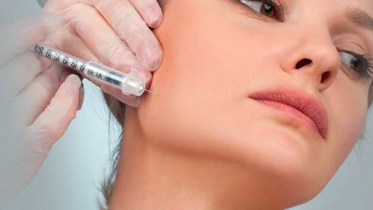 Dental expert inserting botox fillers into woman’s face